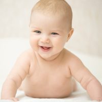 Portrait of a beautiful expressive happy laughing baby, holds head up. Family, baby development concept photo, lifestyle