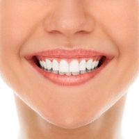 A woman is smiling while being at the dentist